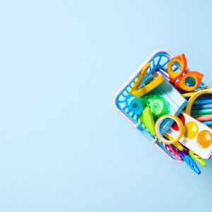 Back to School Concept: A shopping basket filled with colorful school and art supplies on a light blue background with copy space.