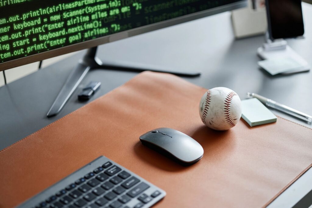Closeup of Computer Mouse and Baseball on Desk with Programming Code Displayed