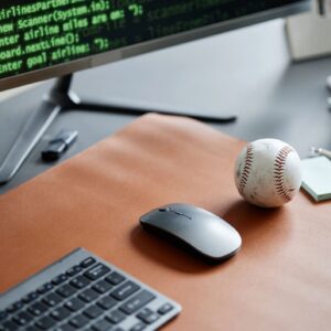 Closeup of Computer Mouse and Baseball on Desk with Programming Code Displayed