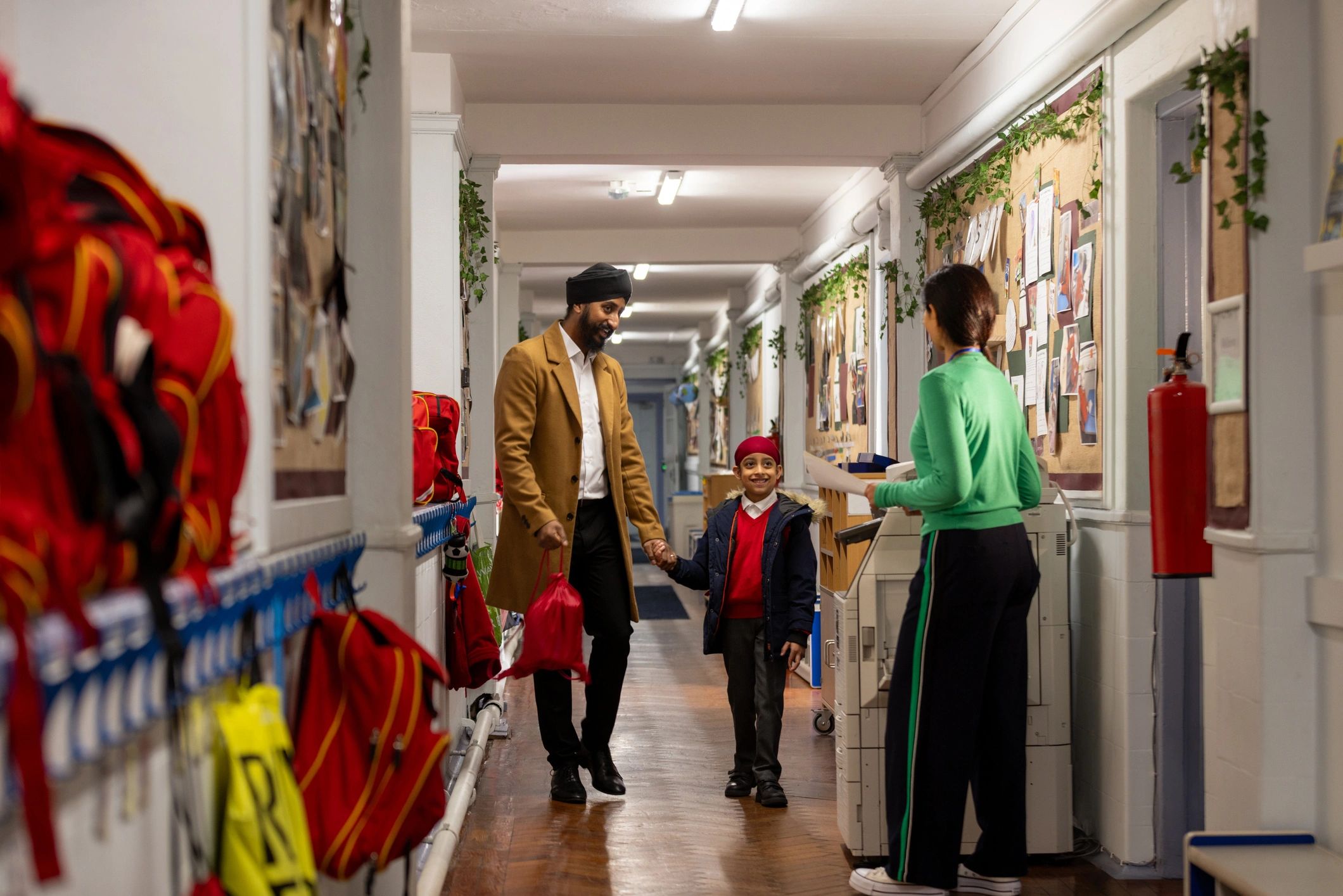Parent and child arriving at school with teacher greeting them