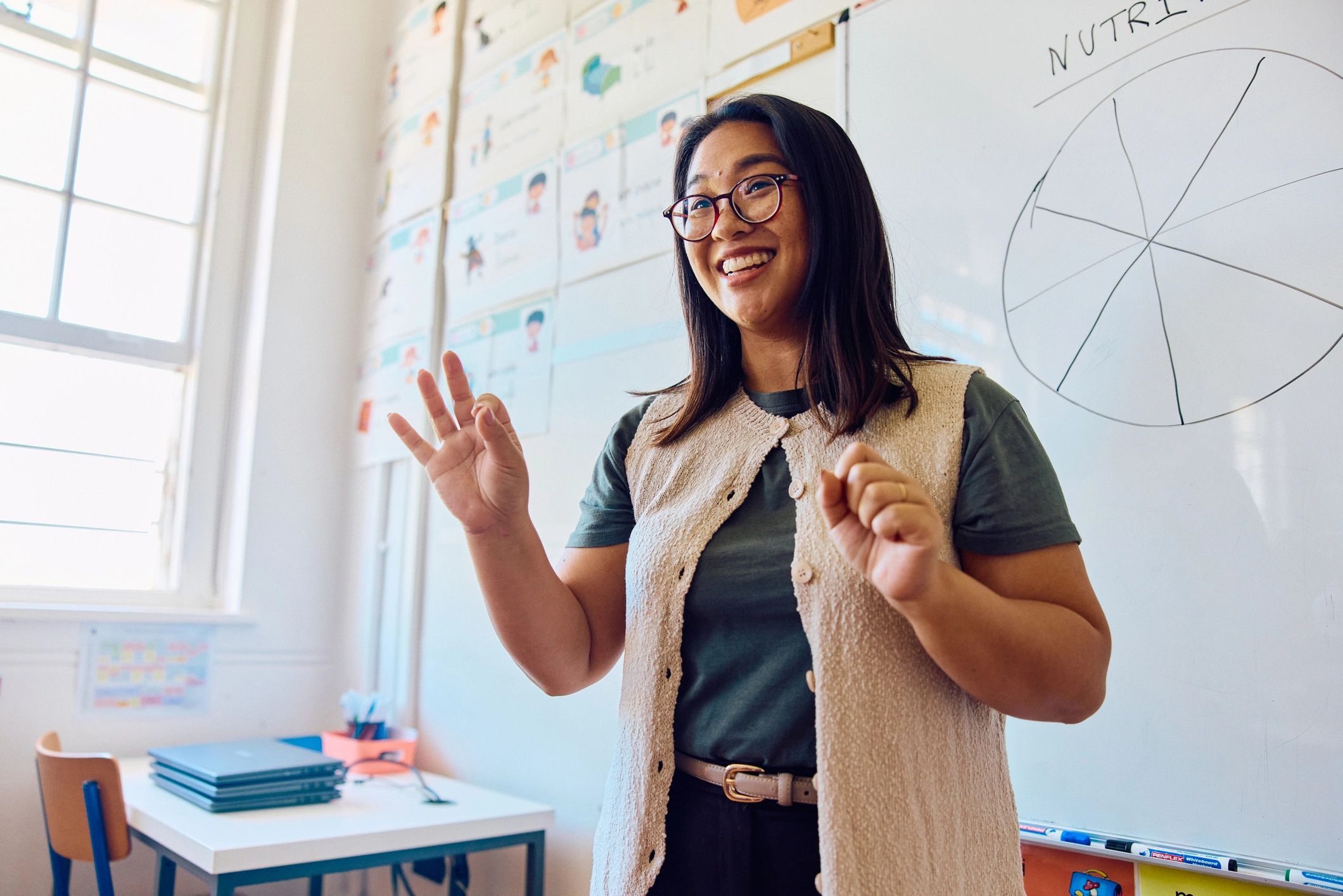 Teacher speaking in classroom beside whiteboard