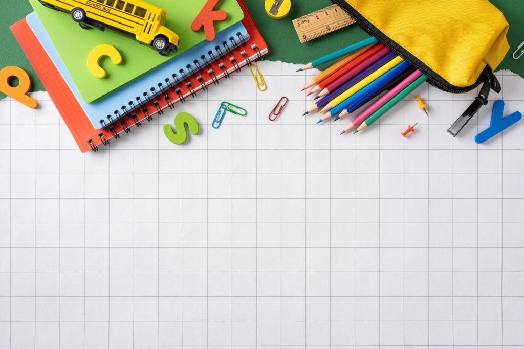 Back to school supplies on grid paper with colorful pencils and notebooks