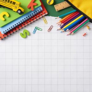Back to school supplies on grid paper with colorful pencils and notebooks