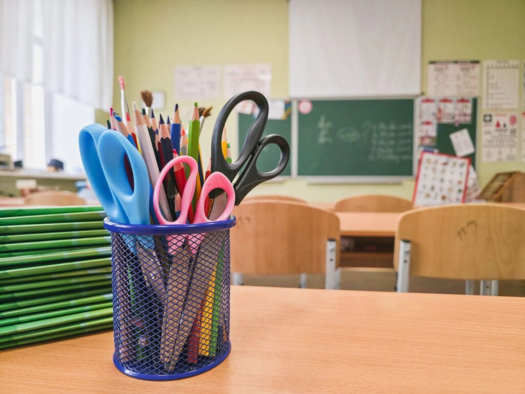 School supplies in stationery holder on classroom desk