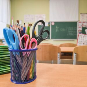 School supplies in stationery holder on classroom desk