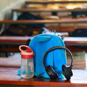 Student Essentials Concept with Blue Backpack, Black Headphones, and Water Bottle on Wooden Table