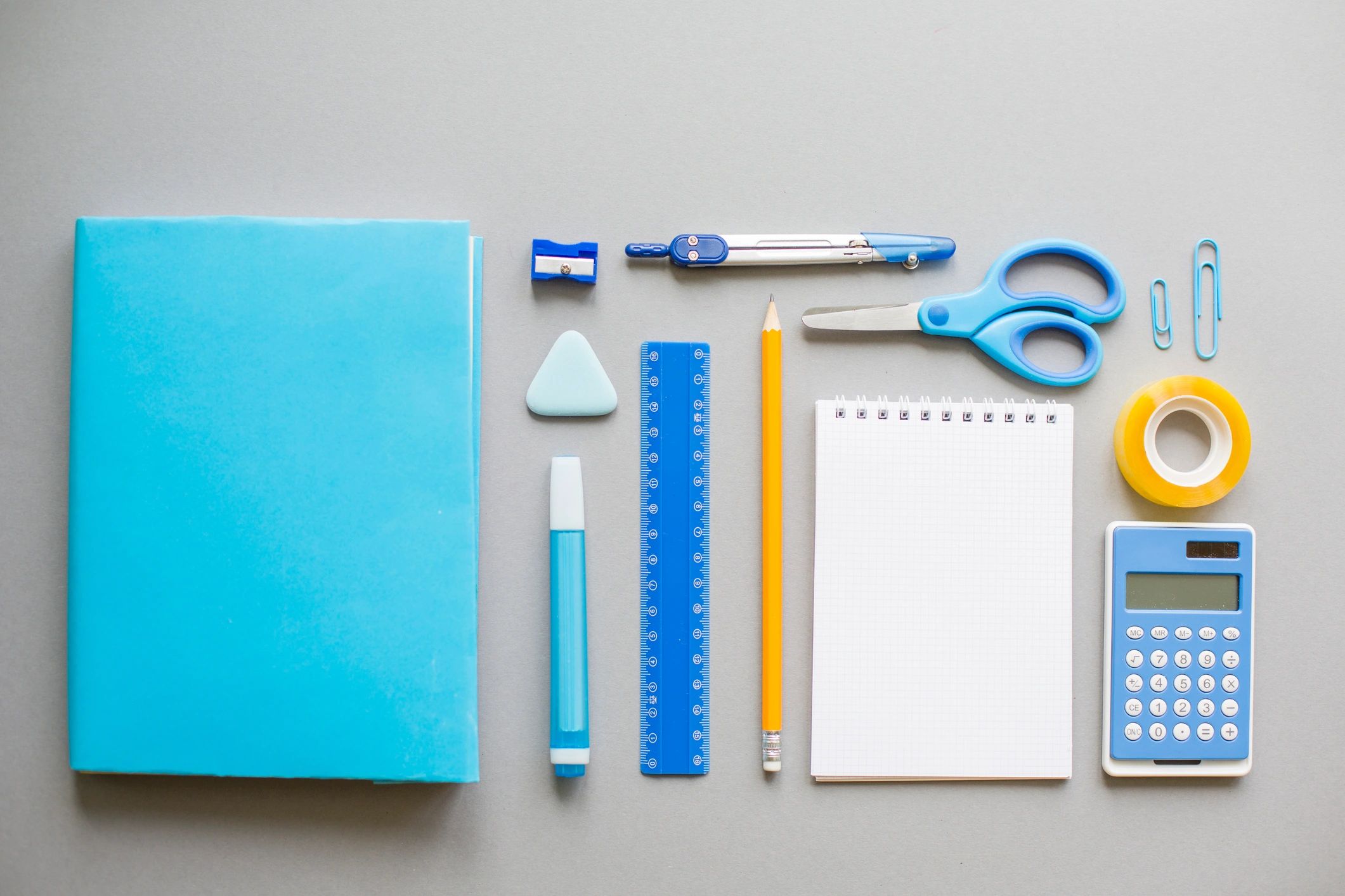Blue school supplies arranged neatly on a grey background