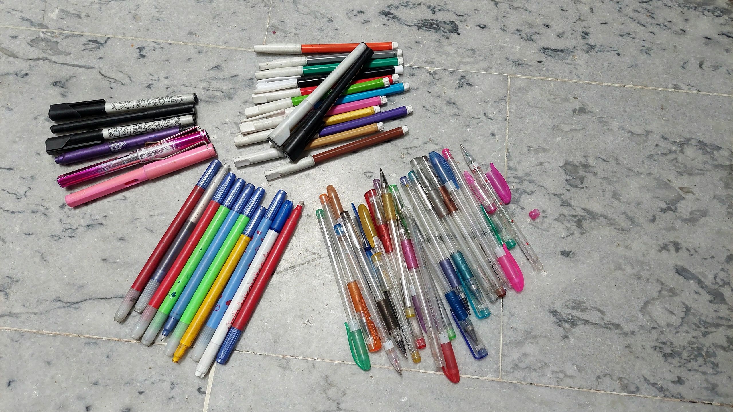 Large assortment of colorful writing pens and school stationery supplies arranged on a clean surface